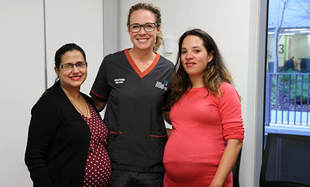 A female registered midwife stands between two pregnant women