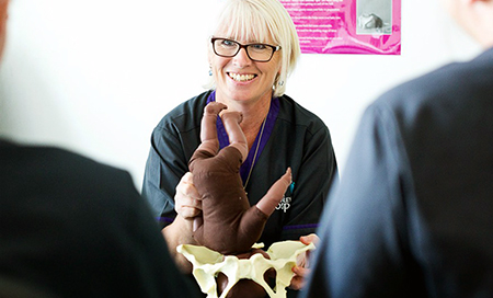 A midwife holds a doll and plastic replica of a female pelvis
