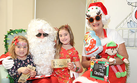 Two young girls with their faces painted stand next to Santa and Mrs Claus